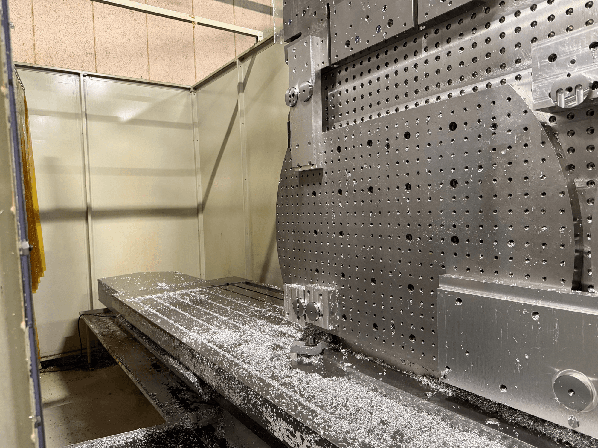 Lähikuva KIHEUNG KNC-U1000 -yleiskoneistuskeskuksen etukuvasta, jossa näkyy metallityöpöytä alumiinilastuilla.