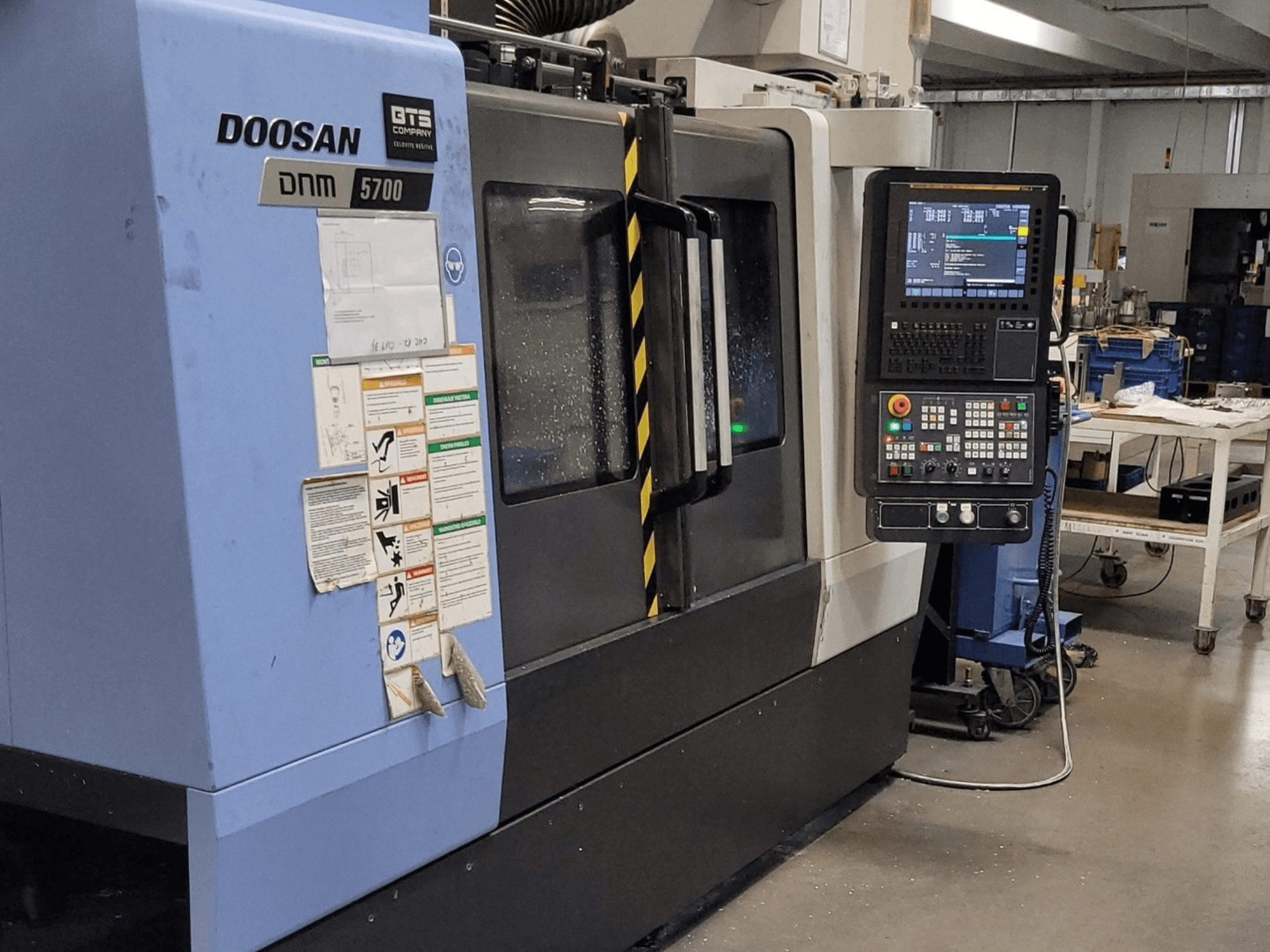 DOOSAN DNM 5700 -pystykoneistuskeskus, etunäkymä, jossa näkyvät ohjauspaneeli ja käyttökytkimet.