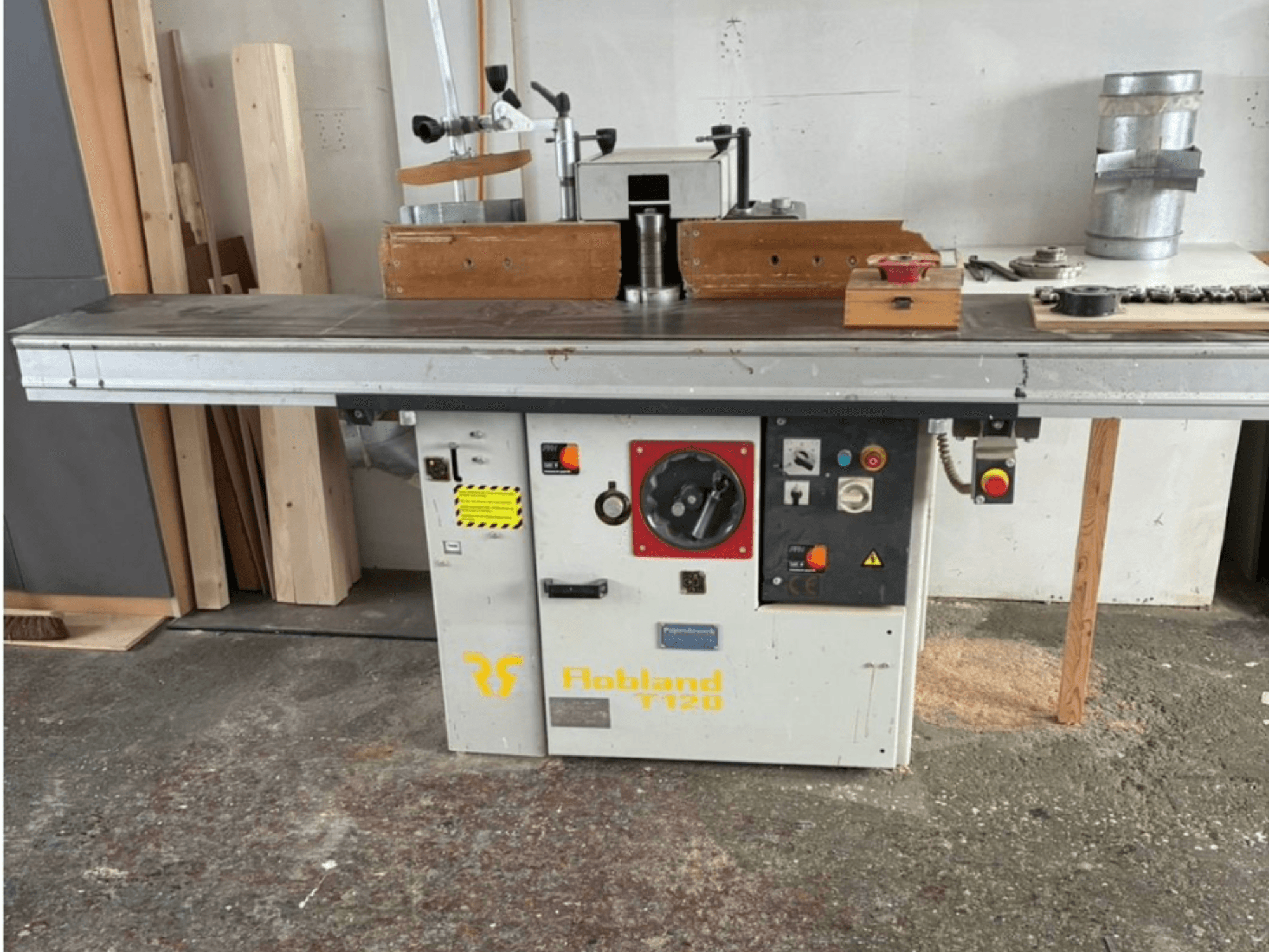 Hobbland T120 pöytähöylässä, etukuva, on hopeinen pinta, ohjauspaneeli painikkeilla ja turvatarroilla.